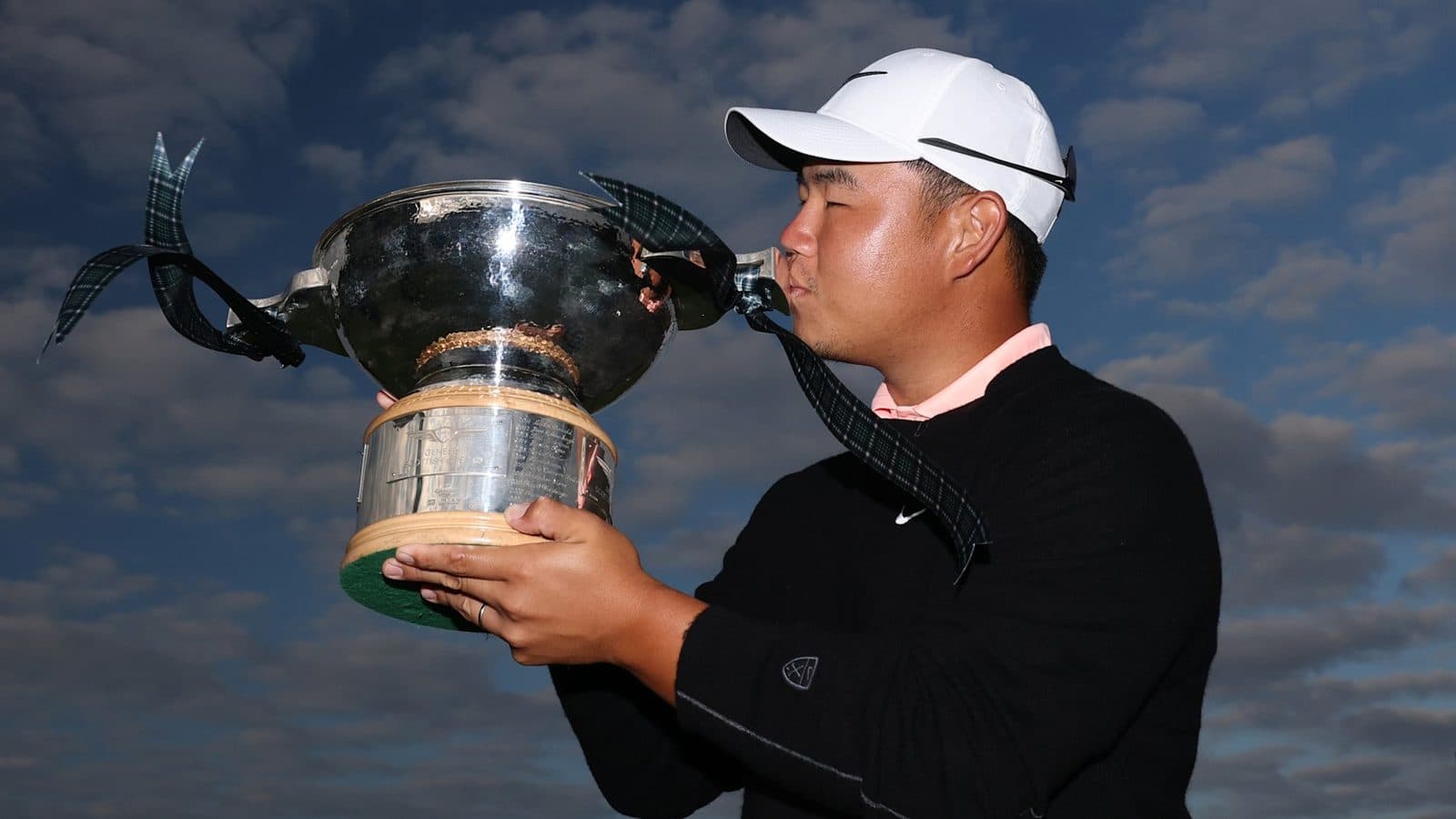 Tom Kim in a white cap, fist raised after winning the Genesis Scottish Open.